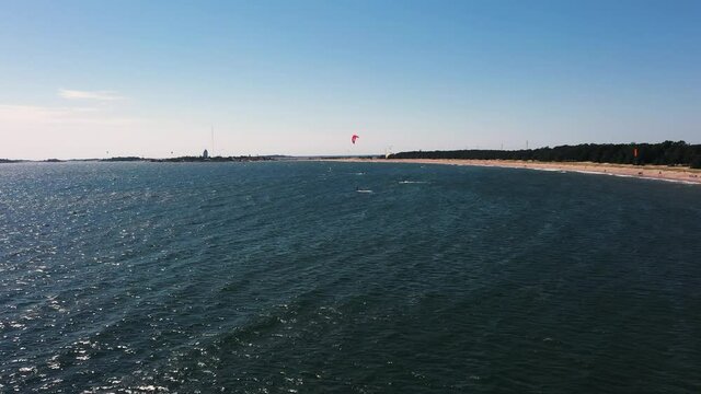 Aerial view of people Kite sailing, at a beach, warm, windy, summer day, in Scandinavia - dolly, drone shot