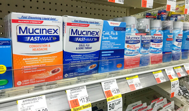 Packs of Mucinex stand on a shelf in a drug store.