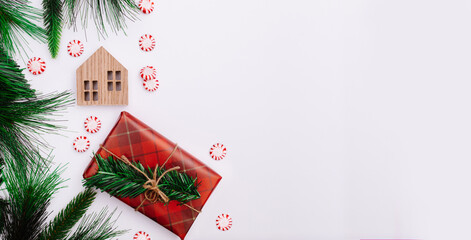 Christmas background. Red wrapped gift with natural cord surrounded by Christmas decorations. Pine tree. Red white and green. New Year background