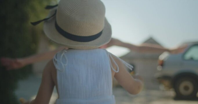 Two years old cute little girl gladly running to her teenage older sister in the streets of an old european town on a sunny day