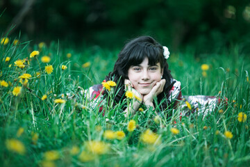 Portrait of teen girl lying in the green grass.