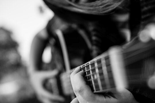 Fingers on the strings, girl playing acoustic guitar. Black and white photo.
