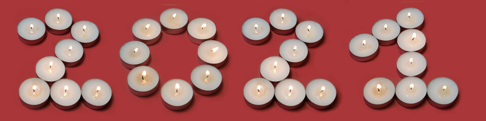 Obraz na płótnie Canvas Happy New Year 2021. Creative Number 2021 with white candles burning isolated on red background for design. Beautiful Glowing for holiday greeting card. Topview.