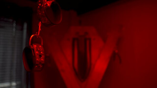 Bondage and kinky handcuffs in a red room.