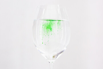 A drop of green liquid was just poured into a clear wineglass