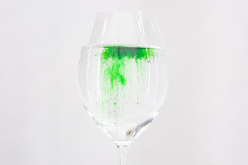 A drop of green liquid was just poured into a clear wineglass