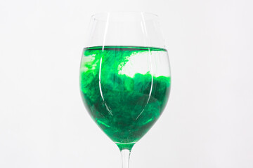 A drop of green liquid was just poured into a clear wineglass