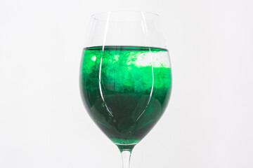 A drop of green liquid was just poured into a clear wineglass