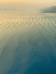 Sunset over a sandy beach by the Pacific Ocean.