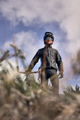 Male cyclist in sportswear, glasses and protective helmet walking with his bike in the forest to take a break after riding. 