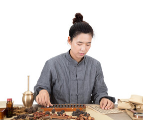 A young Chinese doctor at the table in front of a white background is busy grabbing medicine