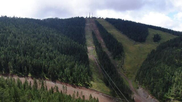 Aerial view of gondola ski lift route to Tornik peak of Zlatibor mountain Serbia on summer day. Green evegreen forest under cloudy sky, drone shot