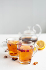 Winter hot tea to strengthen the immune system. Two glass cups in which pour hot tea from the kettle on a white background. Selective focus.