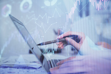 Multi exposure of woman hands typing on computer and financial graph hologram drawing. Stock market...