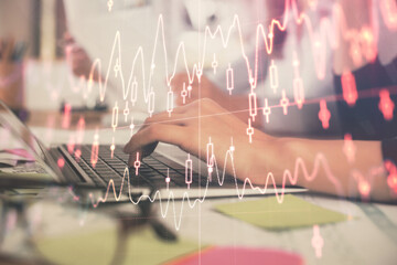 Multi exposure of woman hands typing on computer and financial graph hologram drawing. Stock market...