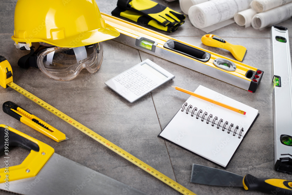 Wall mural contractor concept. tool kit of the contractor: yellow hardhat, libella, hand saw. plans and noteboo