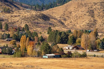 This image shows an idyllic rural Idaho homestead amongst a rolling hills autumn colored landscape.