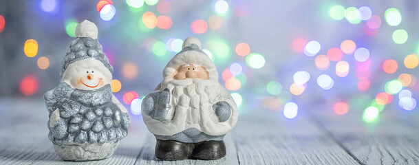 Christmas greeting card with decorative cute snowman and Santa Claus. Bokeh effect on background. Horizontal banner