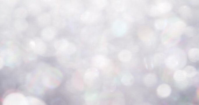 Luxurious soft white background with glittering floating particles and a shiny rainbow reflection.