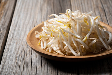 Bean sprouts in a wooden plate set against an old wooden background