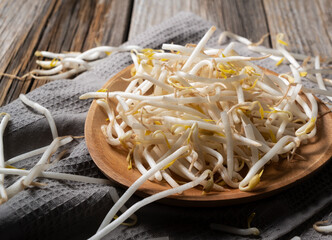 Bean sprouts in a wooden plate set against an old wooden background