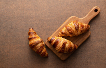 Croissant on a wooden chopping board with a wooden background