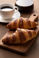 Croissants and coffee on a wooden cutting board