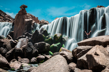 Female tourist sitting on a rock at the Pillones Waterfall in Stone Forest of Imata