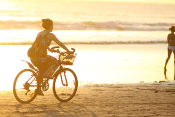 Obraz premium Girl ride bike on the beach at sunset time