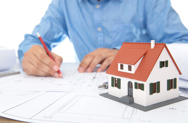 The architect is looking at the drawings and has a small house model beside it