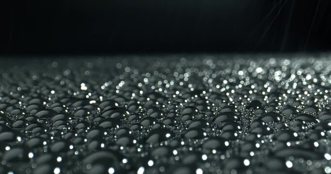  Light reflection in the drops on black background. Faling drops on glossy surface. Abstract wet surface. Point of View.