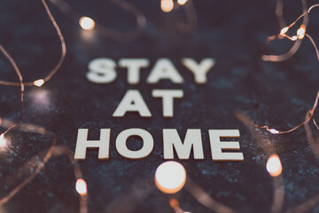 Fototapeta na wymiar holidays in lockdown due to covid, golden fairy lights surrounding message about staying at home