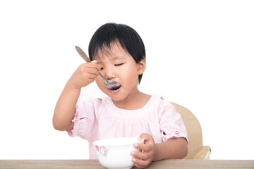 Chinese little girl eating by herself with a spoon