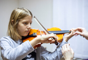 helping the teacher to keep his hand on the violin correctly, placing children's hands when playing the violin