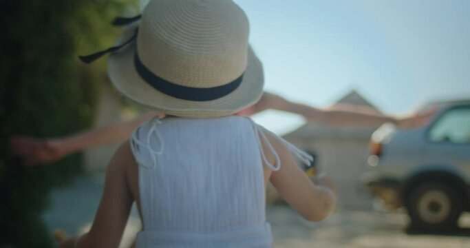 Cute little two years old girl happily running to hug her older little sister in the street of an old european town on a sunny day in summer