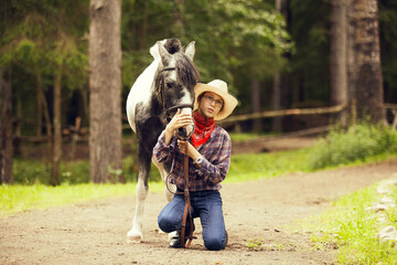 Fototapeta premium Young girl and the horse in the forest. Equestrian girl. Cowgirl