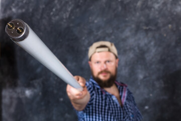 Solid bearded man at casual clothes with a fluorescent lamp looks like stick