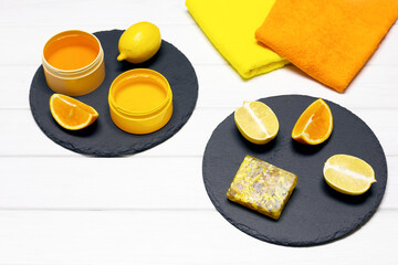 Natural organic skin care cosmetics concept. Homemade citrus soap with lemons, oranges and towels on white wooden board table. Copy space