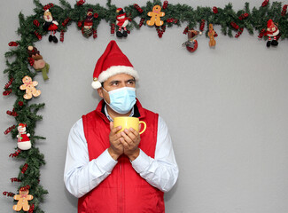 latin man with protection mask and cup of coffee in christmas decoration, new normal covid-19