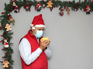 latin man with protection mask and cup of coffee in christmas decoration, new normal covid-19