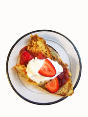 Breakfast of french toast topped with strawberries and whipped cream