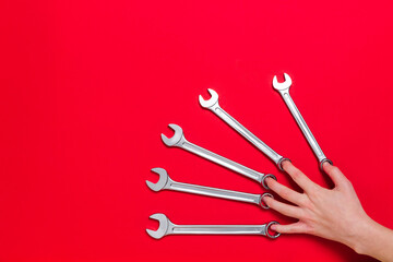 Set of wrenches different size and man hand lays on a red background. Banner with tools and the place for text with industrial holiday concept. Close-up
