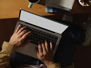 Male hands typing on laptop keyboard on his lap while sitting at workplace, clipping path