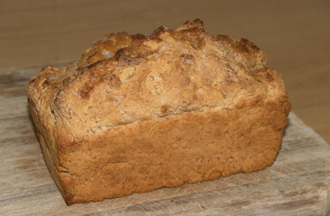 A loaf of beer bread isolated on a wooden cutting board image in horizontal format