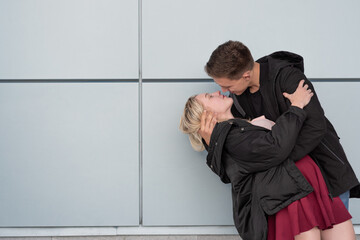 Happy young couple kissing while standing near gray wall