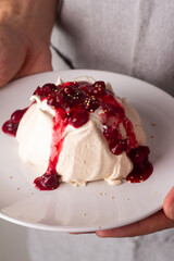 meringue with cream and red berries in male hands
