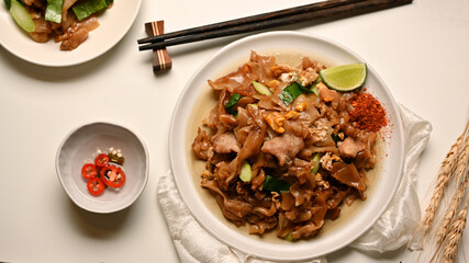 Stir fried Noodle with sweet soy sauce (Pad See Ew) with seasoning on dinning table