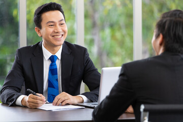 Young handsome businessman smiling during discussion of planing together with his team in the office. Concept of business. Selective focus on a  man on the left.