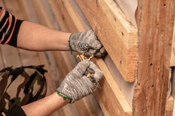 A worker installs drywall for a wall in a room.