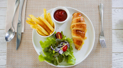 Croissants with vegetable salad and Deep potatoes french fried with tomato sauce.